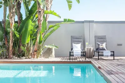 a swimming pool with two chairs and a table next to a house at Bliss Boutique Hotel in Cape Town