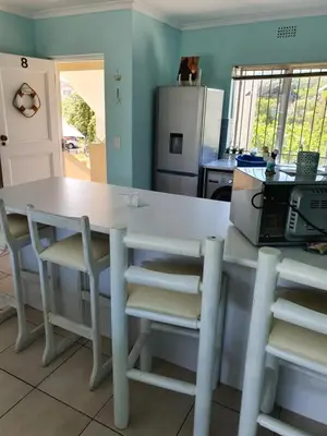 a kitchen with a white table and chairs at Sea and Mountain View Apartment in Gordonʼs Bay