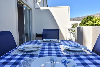 a table with a blue and white checkered table cloth at Sea and Mountain View Apartment in Gordonʼs Bay
