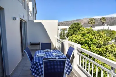 a blue and white table and chairs on a balcony at Sea and Mountain View Apartment in Gordonʼs Bay