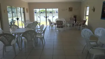a dining room with tables and chairs and windows at Sea and Mountain View Apartment in Gordonʼs Bay