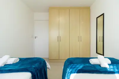 a bedroom with two beds and a cabinet at Citystay Apartments Century City in Cape Town