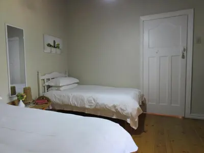 two beds in a room with white walls and a door at Modderkloof Farm Accommodation in Paarl