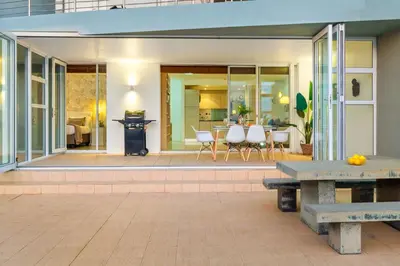 a patio with white chairs and a table at Horizon Bay 103 in Bloubergstrand