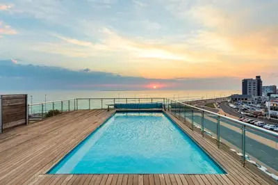 a swimming pool on the roof of a building with the ocean at Horizon Bay 103 in Bloubergstrand