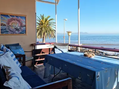 a room with a table and a view of the ocean at Bikini Beach Holiday Home, On the Beach, Sleeps 9! in Gordonʼs Bay