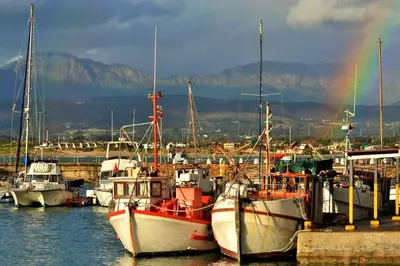 a group of boats docked in a harbor with a rainbow at Bikini Beach Holiday Home, On the Beach, Sleeps 9! in Gordonʼs Bay