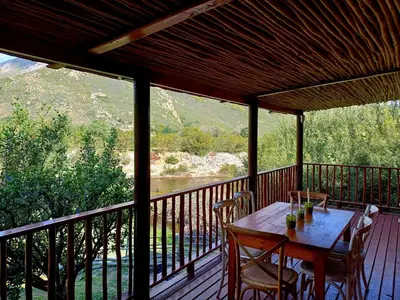 a wooden table on a deck with a view of a river at The River Siding in Wolseley