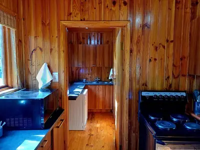 a kitchen with wooden walls and a stove top oven at The River Siding in Wolseley