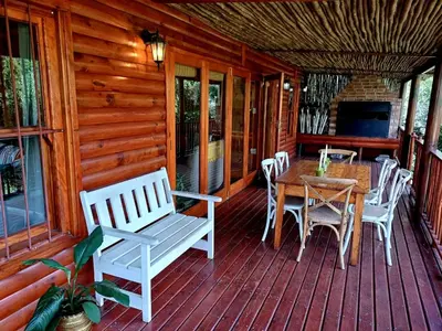 a wooden porch with a table and chairs on it at The River Siding in Wolseley
