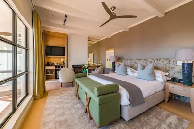 a bedroom with a large bed with a green chair at La Petite Ferme in Franschhoek