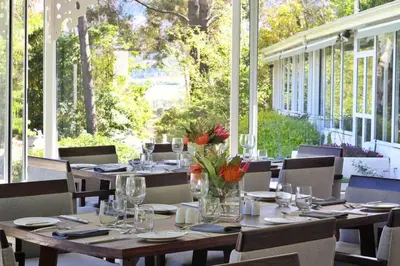 a dining room with tables and chairs on a porch at La Petite Ferme in Franschhoek