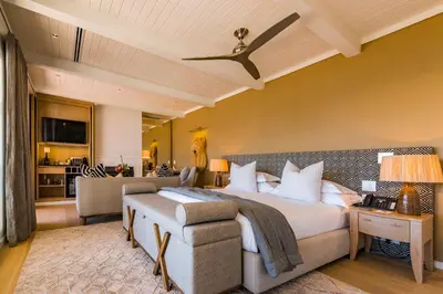 a bedroom with a bed and a living room at La Petite Ferme in Franschhoek