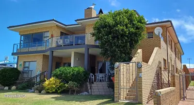 a yellow brick house with a fence in front of it at Kleinmond Panorama Holidays in Kleinmond