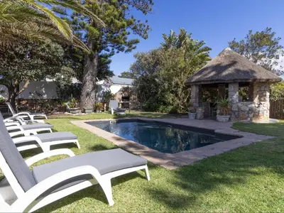a swimming pool with a gazebo and white chairs at House on Westcliff in Hermanus