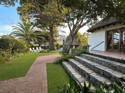 a garden with a brick walkway next to a house at House on Westcliff in Hermanus