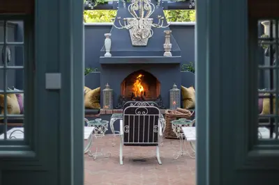 a table and chairs in front of a fireplace at Akademie Street Boutique Hotel in Franschhoek