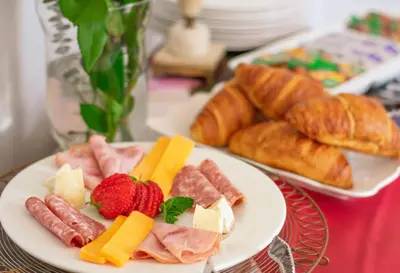 a plate of food with meats and cheese and bread at Rozenburg Guest House in Stellenbosch