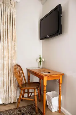 a wooden desk with a chair and a television on a wall at Rozenburg Guest House in Stellenbosch