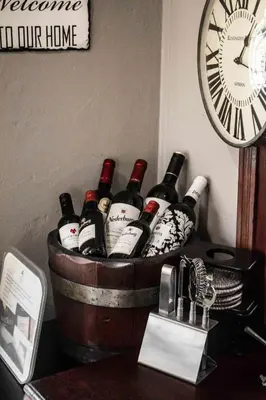 a bunch of wine bottles in a barrel with a clock at Wild Olive Guest House & Villa in Cape Town