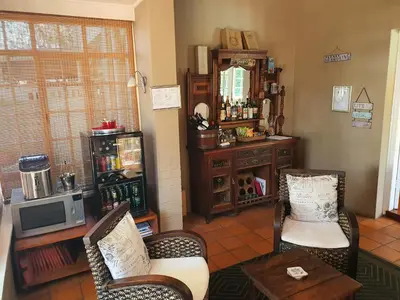 a living room with two chairs and a tv at Wild Olive Guest House & Villa in Cape Town