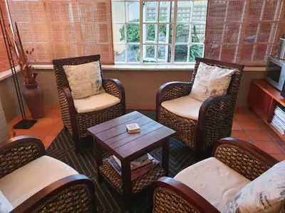 a waiting room with chairs and a table and a tv at Wild Olive Guest House & Villa in Cape Town