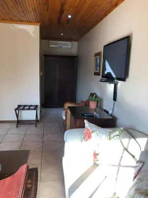 a living room with a white couch and a flat screen tv at Oak Tree Lodge in Paarl