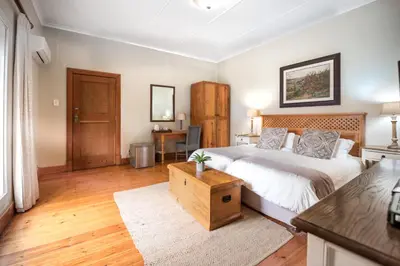 a bedroom with a large bed and a desk at Oak Tree Lodge in Paarl