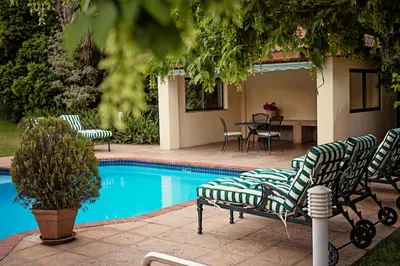 a pool with chairs and a table and a table and chairs at Oak Tree Lodge in Paarl