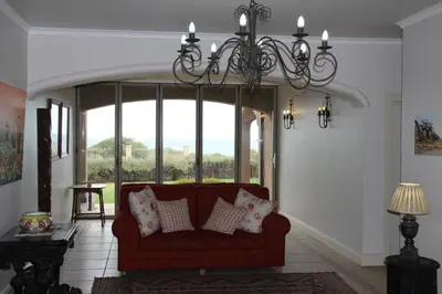a living room with a red couch and a chandelier at On The Cliff Guest House in Hermanus