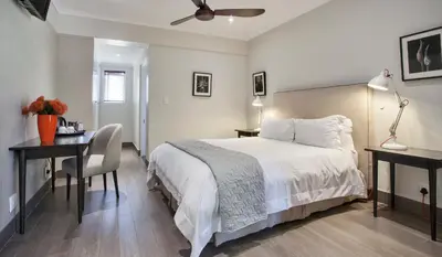 a bedroom with a bed and a desk with a chair at Sugarbird Manor in Stellenbosch
