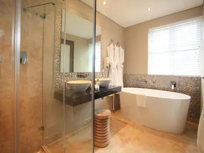 a bathroom with two sinks and a tub and a shower at Abalone Guest Lodge in Hermanus