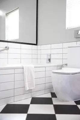 a bathroom with a white toilet and a black and white floor at Protea Hotel by Marriott Franschhoek in Franschhoek