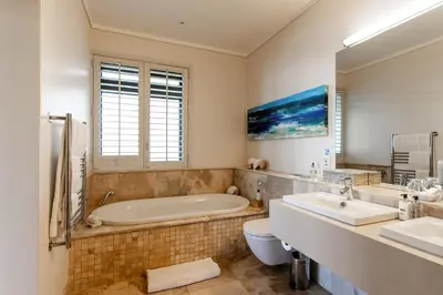 a bathroom with a tub and a toilet and a sink at Selkirk House in Hermanus