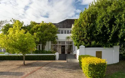 a white house with trees in front of it at Wild Mushroom Country House in Stellenbosch