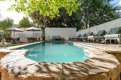 a swimming pool with chairs and an umbrella at Evergreen Manor and Spa in Stellenbosch