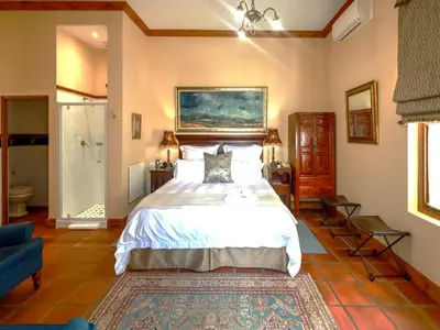 a bedroom with a large bed and a bathroom at Evergreen Manor and Spa in Stellenbosch
