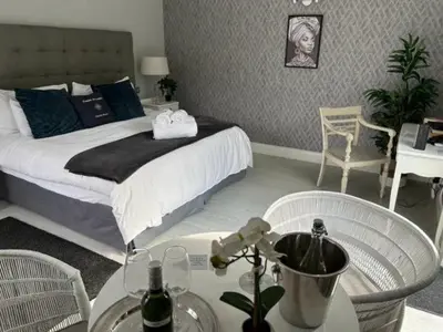 a bedroom with a bed and a table and chairs at OCEAN BREEZE SUNSET BEACH - Cape Town in Cape Town