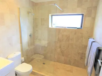 a bathroom with a shower with a toilet and a window at OCEAN BREEZE SUNSET BEACH - Cape Town in Cape Town