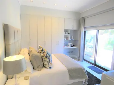 a white bedroom with a bed and a window at OCEAN BREEZE SUNSET BEACH - Cape Town in Cape Town