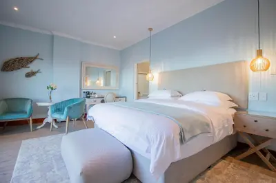 a bedroom with a large bed and a table and chairs at Lavender Manor Guest Lodge in Hermanus