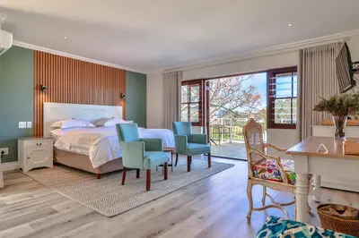 a bedroom with a bed and chairs and a desk at Lavender Manor Guest Lodge in Hermanus
