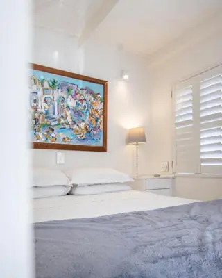 a bedroom with a bed with a painting on the wall at Le Grenier Luxury Loft in Franschhoek