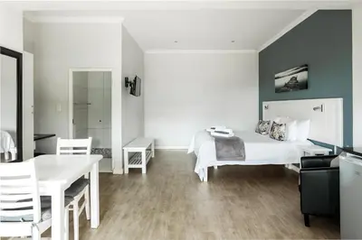 a bedroom with a white bed and a table and chairs at Bona Vista Self-Catering Accommodation in Klapmuts