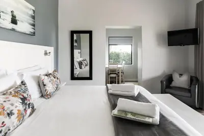 a bedroom with a large white bed and a chair at Bona Vista Self-Catering Accommodation in Klapmuts