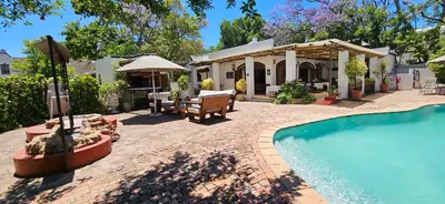 a backyard with a swimming pool and a house at De Leeuwenhof Estate in Paarl