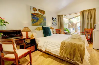 a bedroom with a bed and a desk with a computer at John Bauer Pottery Studio in Cape Town