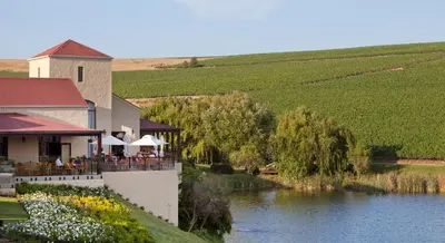 a restaurant next to a river next to a building at ASARA Wine Estate & Hotel in Stellenbosch