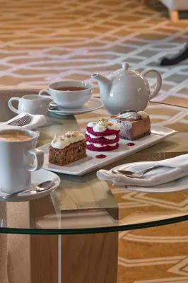 a glass table with cakes and cups of coffee at ASARA Wine Estate & Hotel in Stellenbosch