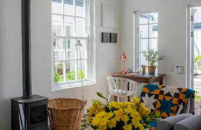 a living room with a fireplace and a chair with flowers at The Vishuis in Hermanus